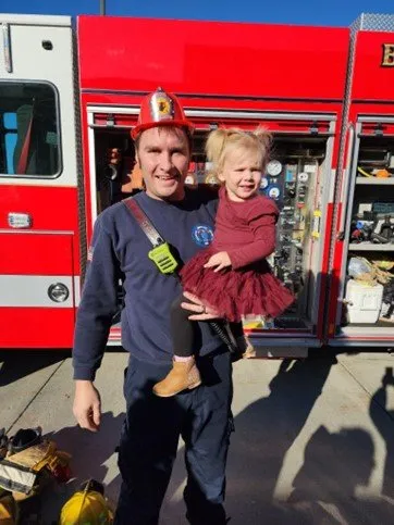 fireman with young girl near fire truck